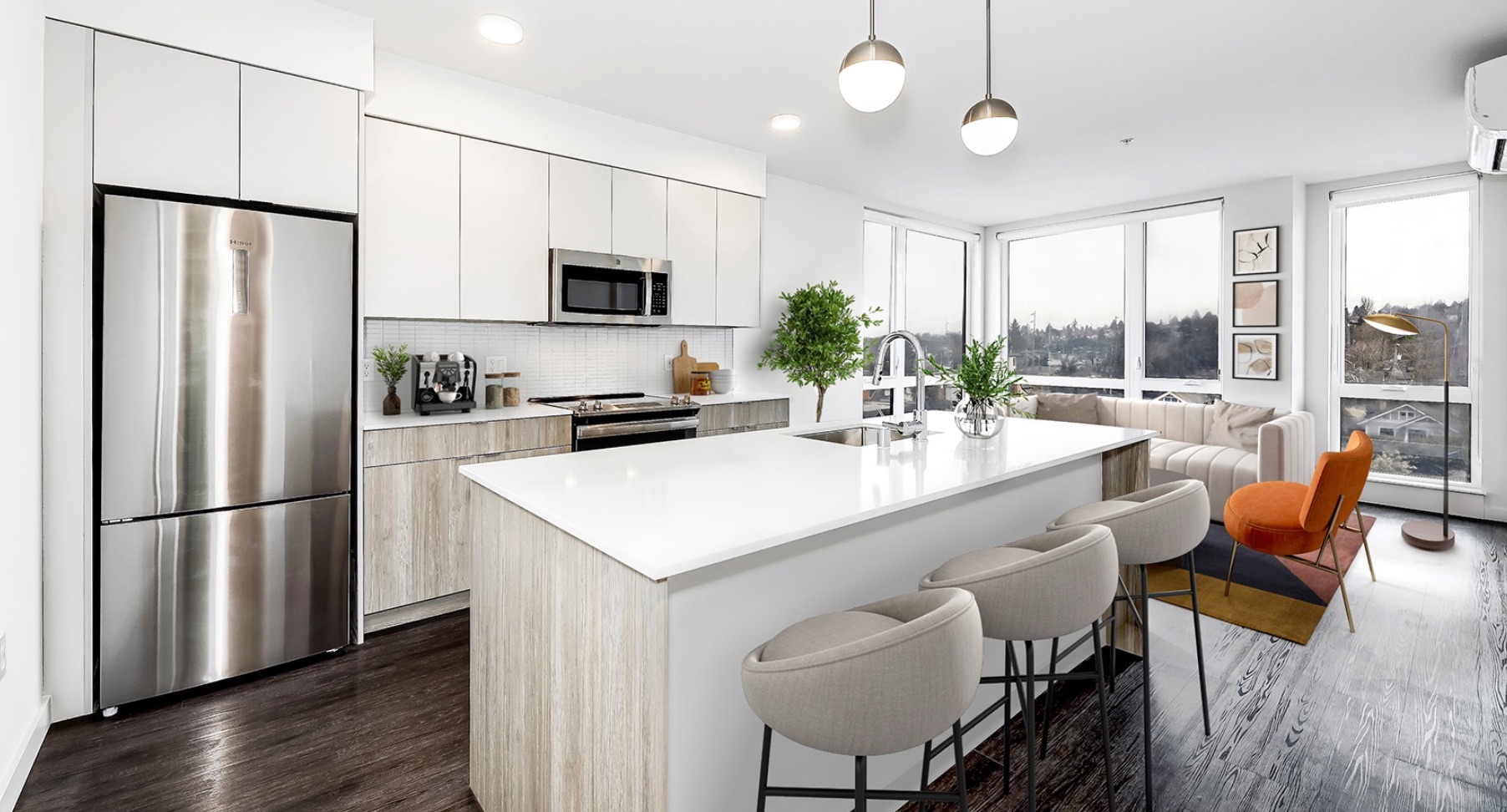 Modern open-plan kitchen with light cabinetry, island seating, stainless appliances, and large windows